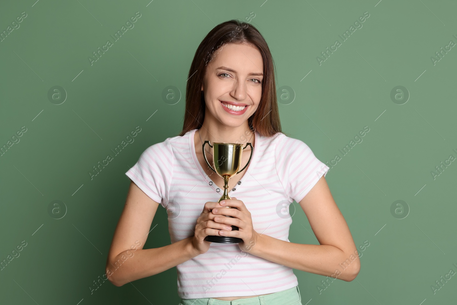 Photo of Happy winner with gold trophy cup on green background