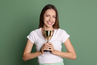 Happy winner with gold trophy cup on green background