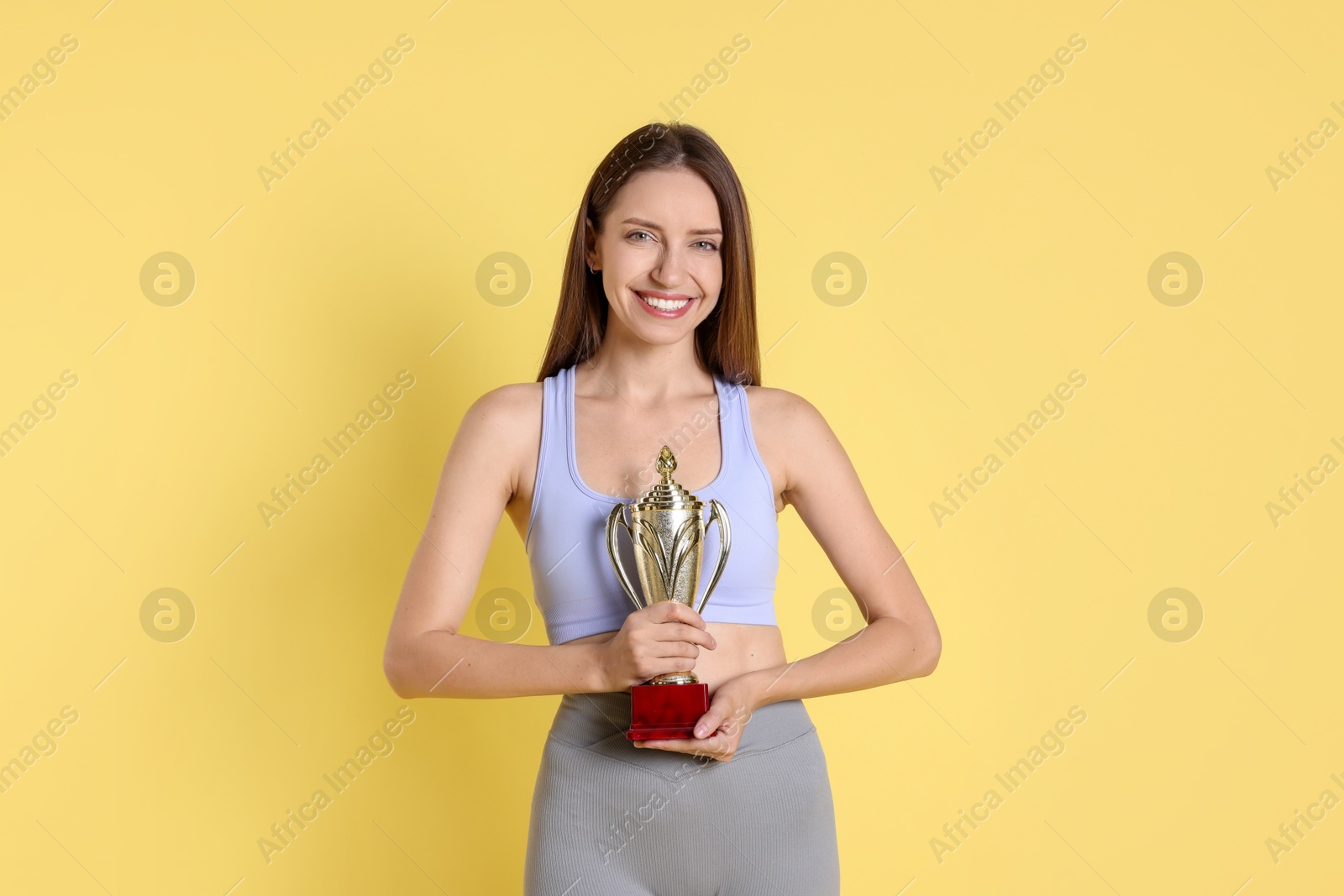 Photo of Happy winner with gold trophy cup on yellow background