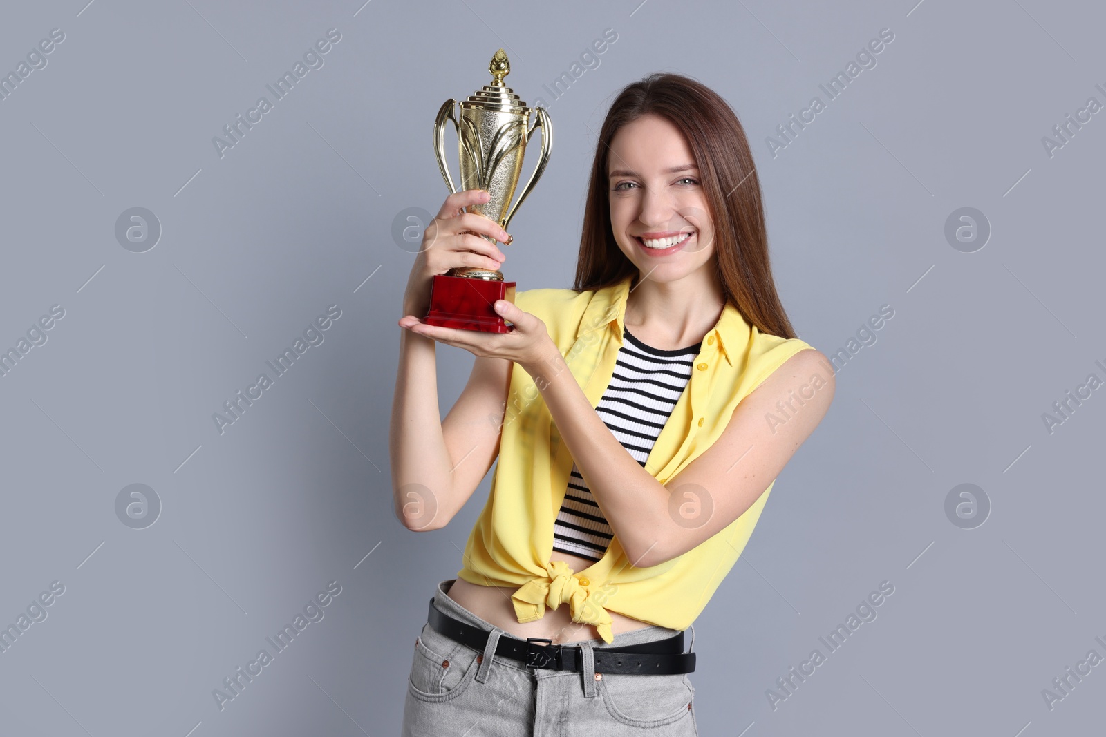 Photo of Happy winner with gold trophy cup on gray background