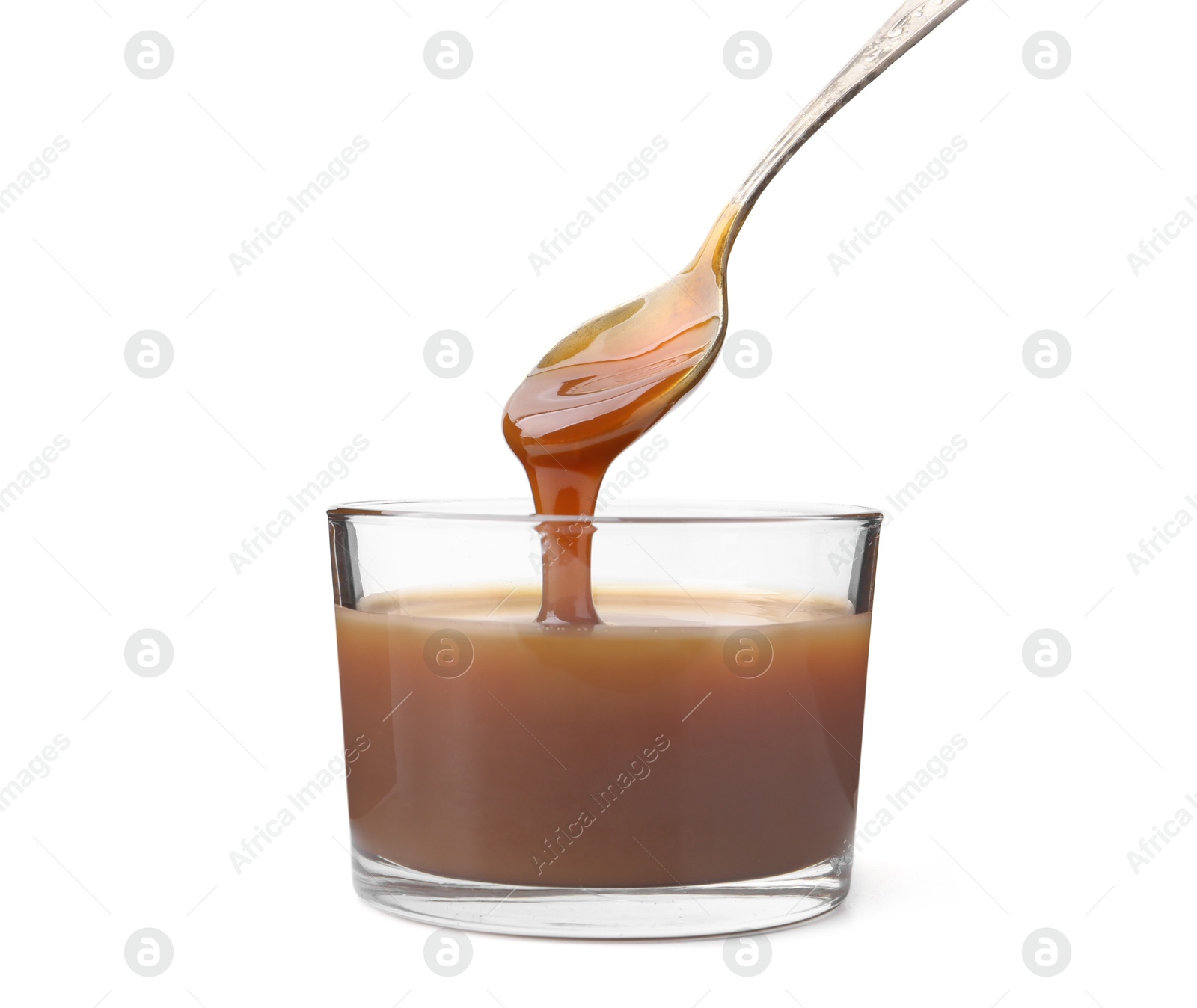 Photo of Tasty caramel sauce dripping from spoon into glass bowl on white background, closeup