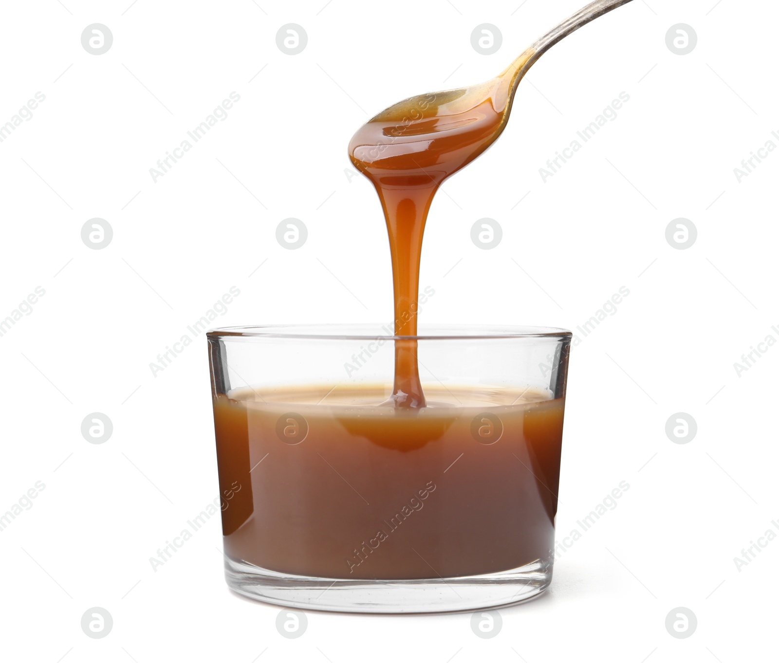 Photo of Tasty caramel sauce dripping from spoon into glass bowl on white background, closeup