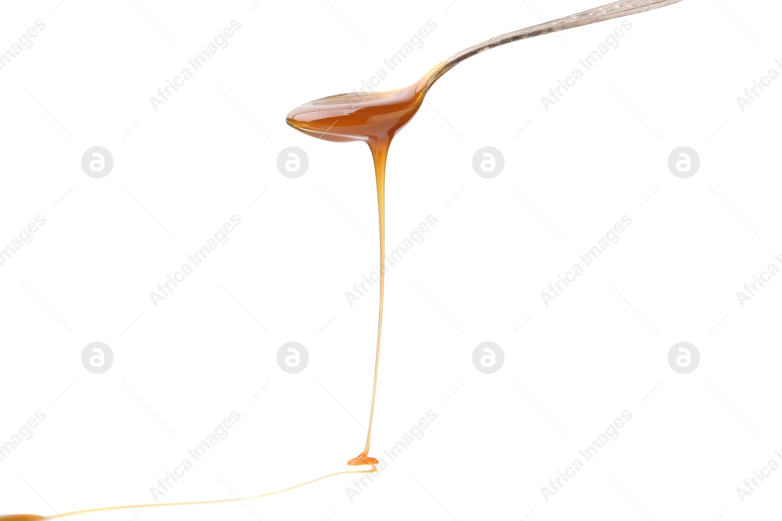 Photo of Tasty caramel sauce dripping from spoon on white background, closeup