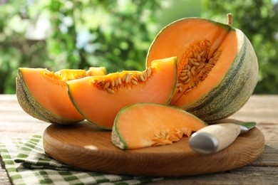 Photo of Cut ripe Cantaloupe melon and knife on wooden table outdoors, closeup