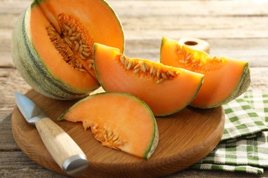 Photo of Cut ripe Cantaloupe melon and knife on wooden table, closeup