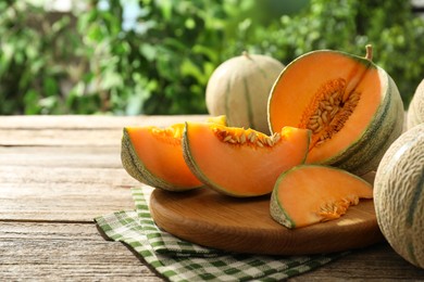 Photo of Whole and cut ripe Cantaloupe melons on wooden table outdoors