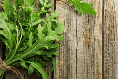 Photo of Bunch of fresh green arugula leaves on wooden table, top view. Space for text