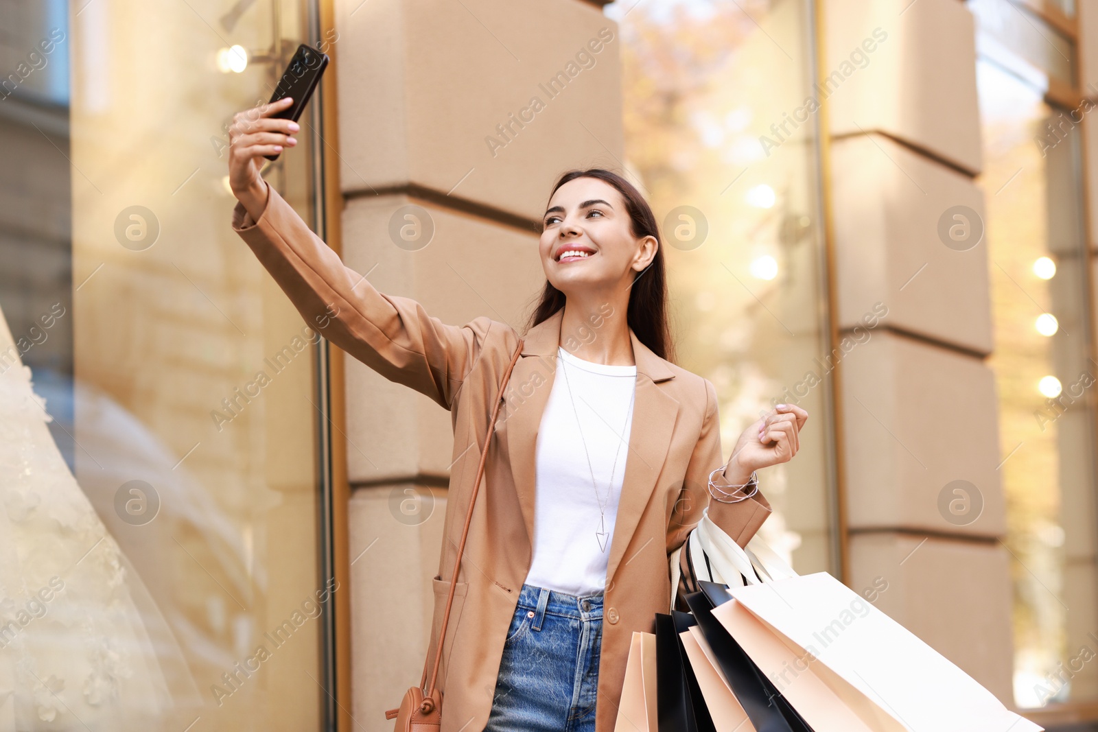 Photo of Happy woman with many shopping bags taking selfie outdoors