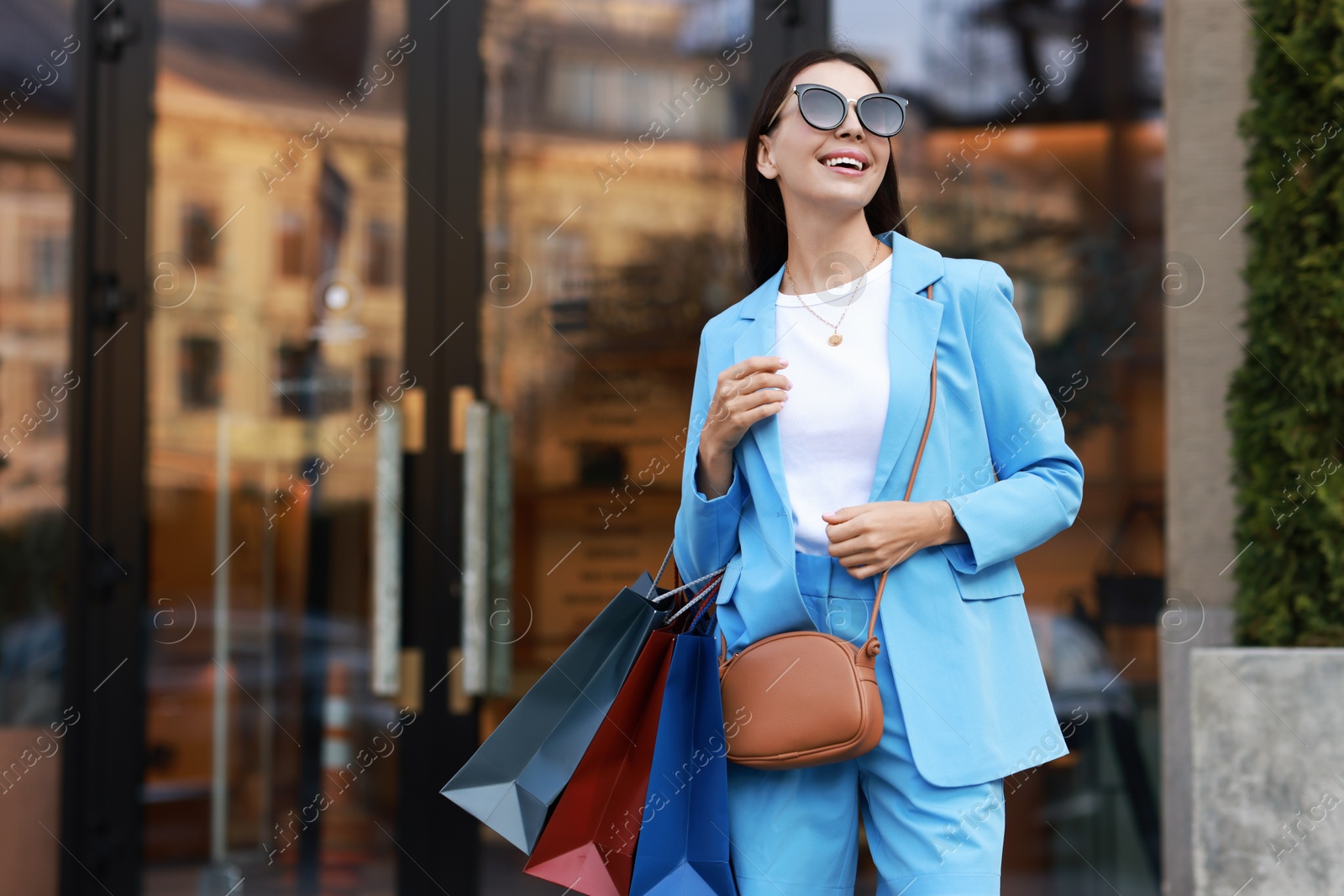 Photo of Happy woman with colorful shopping bags outdoors, space for text