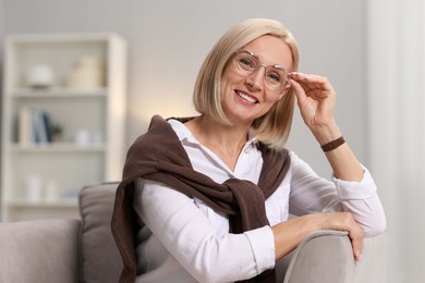 Portrait of smiling middle aged woman sitting on armchair at home