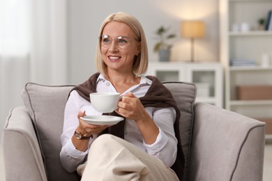 Smiling middle aged woman with cup of hot drink at home