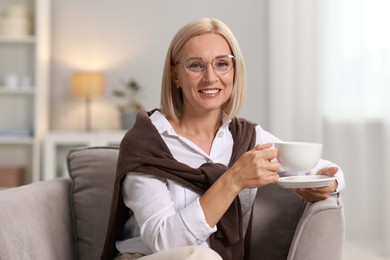 Smiling middle aged woman with cup of hot drink at home