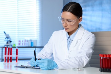 Photo of Laboratory testing. Doctor taking notes at table indoors