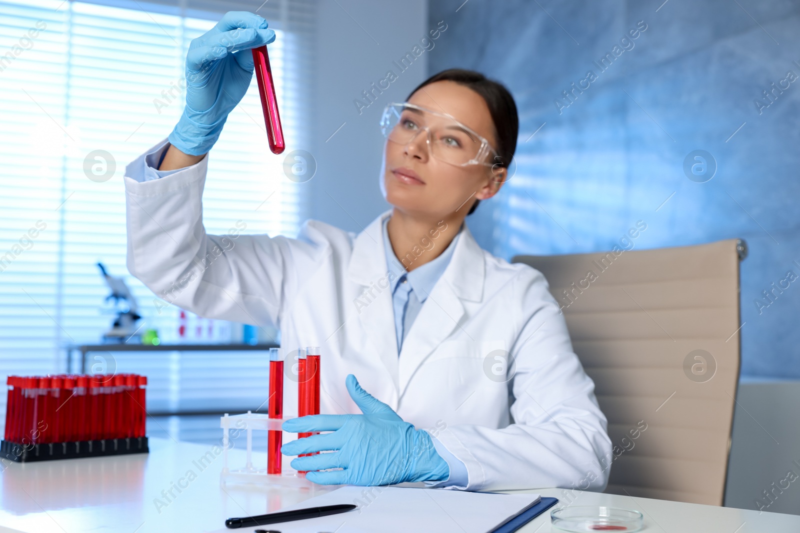 Photo of Laboratory testing. Doctor holding test tube with blood sample at table indoors