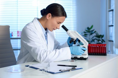 Photo of Laboratory testing. Doctor working with microscope at table indoors