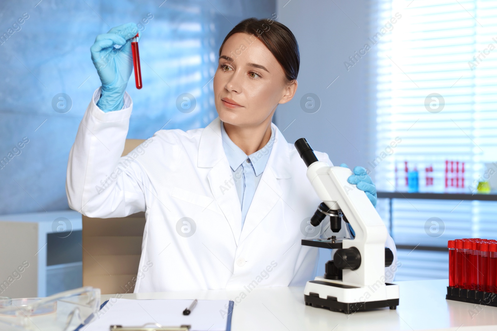 Photo of Laboratory testing. Doctor holding test tube with blood sample at table indoors