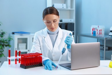 Photo of Laboratory testing. Doctor dripping blood sample into Petri dish at table indoors