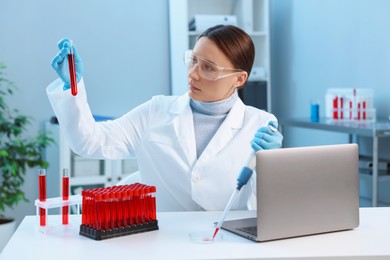 Laboratory testing. Doctor holding test tube with blood sample at table indoors