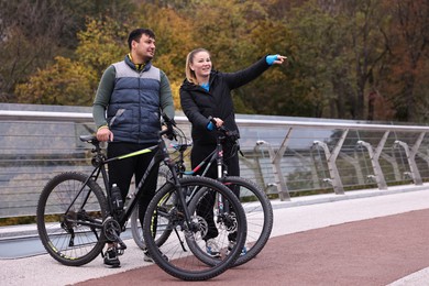 Photo of Beautiful happy couple with bicycles spending time together outdoors, space for text