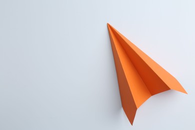 Photo of One handmade orange paper plane on white background, top view. Space for text