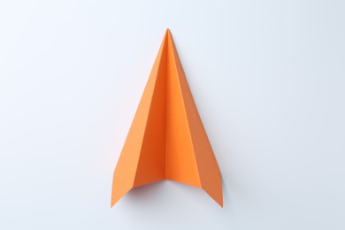 Photo of One handmade orange paper plane on white background, top view