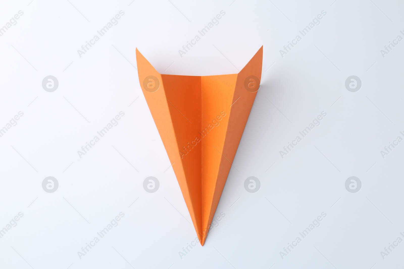 Photo of One handmade orange paper plane on white background, top view