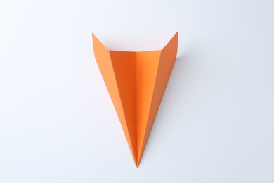 Photo of One handmade orange paper plane on white background, top view