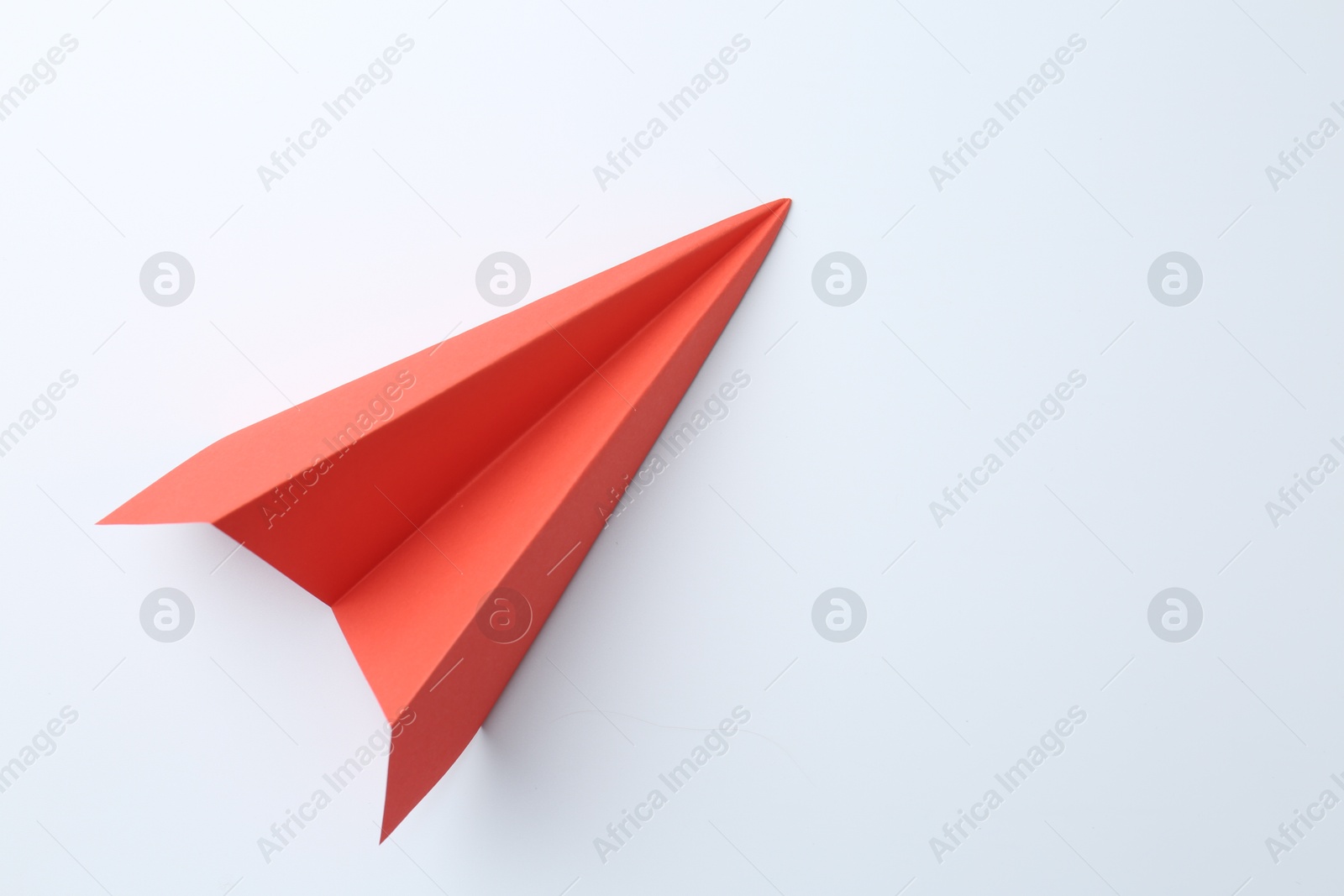 Photo of One handmade coral paper plane on white background, top view. Space for text