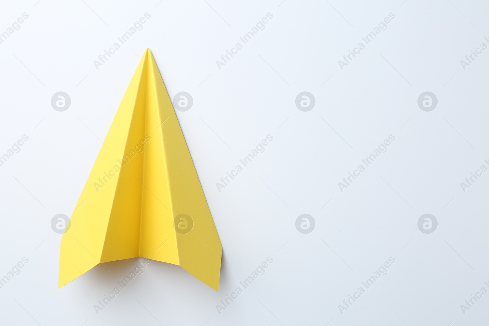 Photo of One handmade yellow paper plane on white background, top view. Space for text