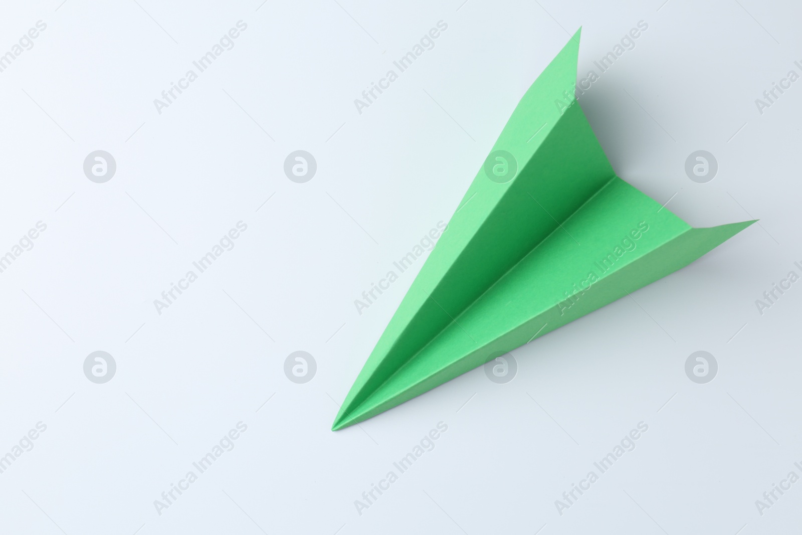 Photo of One handmade green paper plane on white background, top view. Space for text