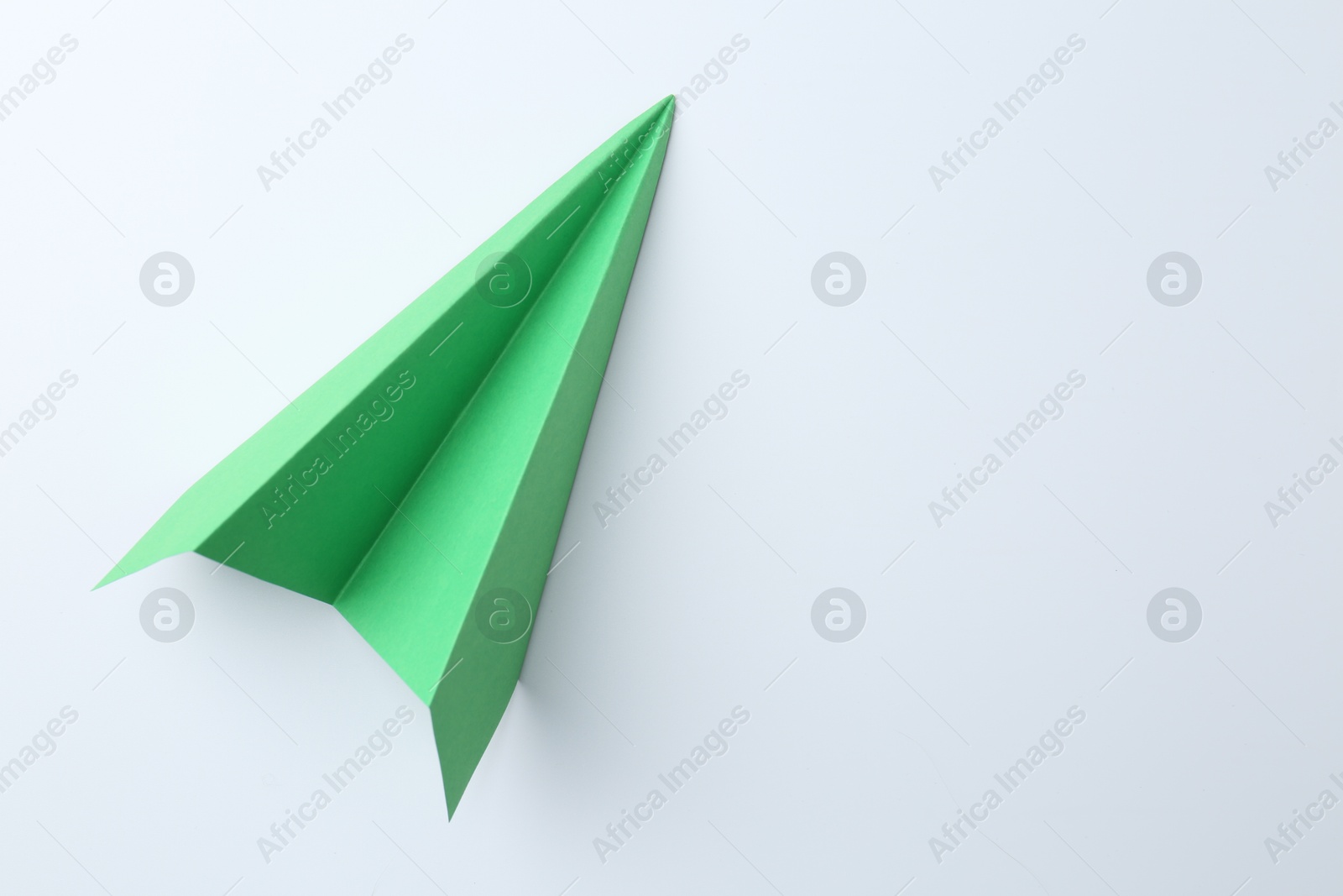 Photo of One handmade green paper plane on white background, top view. Space for text