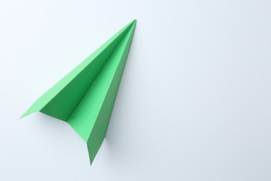 Photo of One handmade green paper plane on white background, top view. Space for text