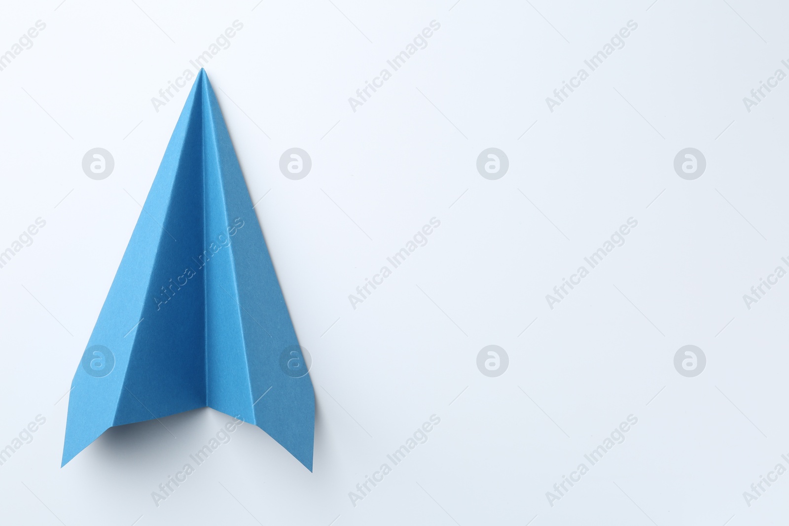 Photo of One handmade light blue paper plane on white background, top view. Space for text