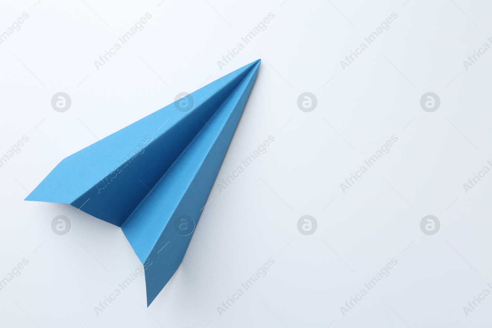 Photo of One handmade light blue paper plane on white background, top view. Space for text