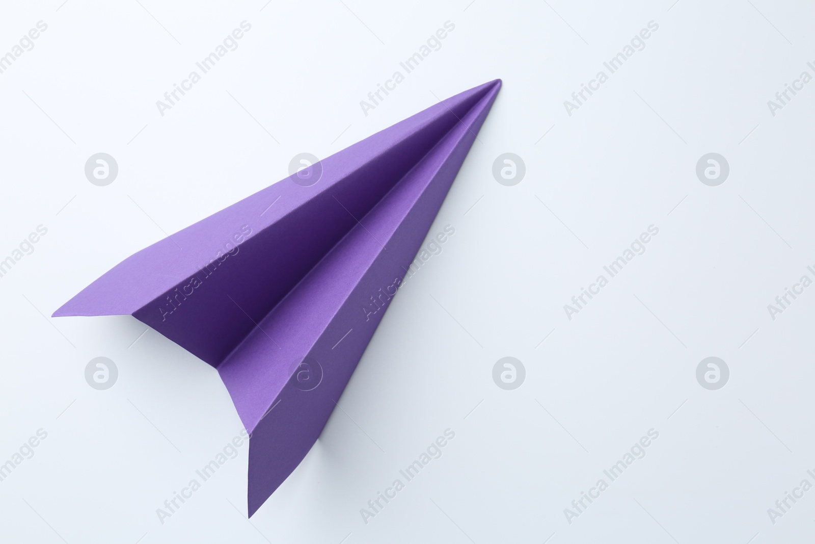 Photo of One handmade purple paper plane on white background, top view. Space for text