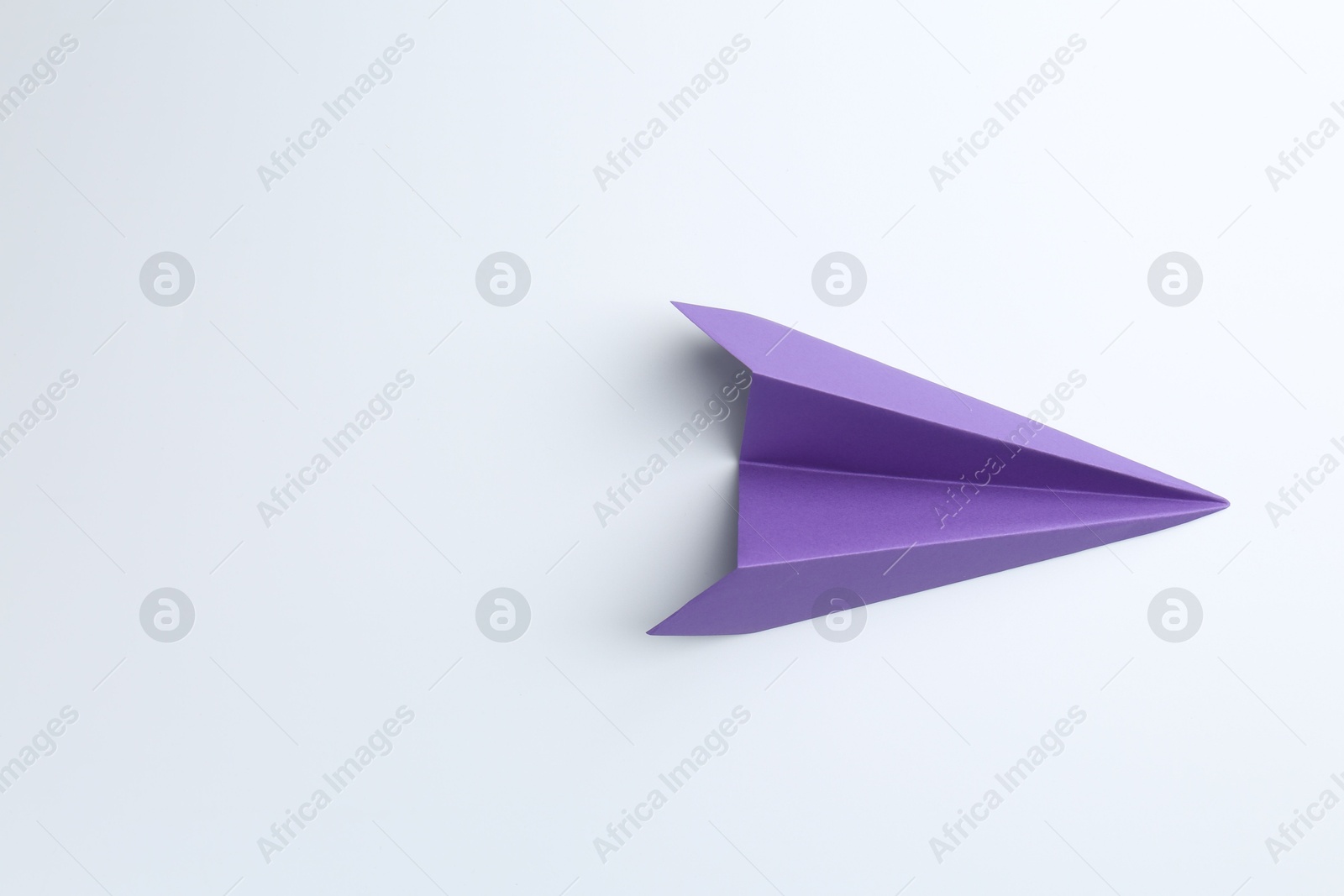 Photo of One handmade purple paper plane on white background, top view. Space for text