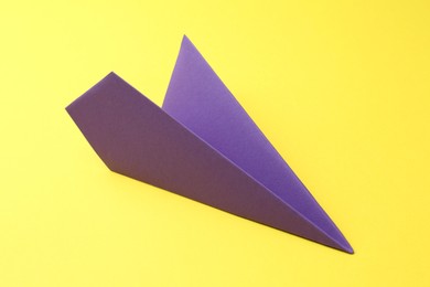 Photo of One handmade purple paper plane on yellow background