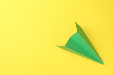 Photo of One handmade green paper plane on yellow background, top view. Space for text