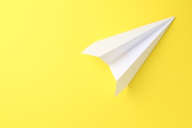 Photo of One handmade paper plane on yellow background, top view. Space for text