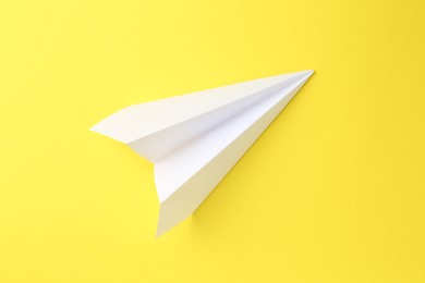 Photo of One handmade paper plane on yellow background, top view