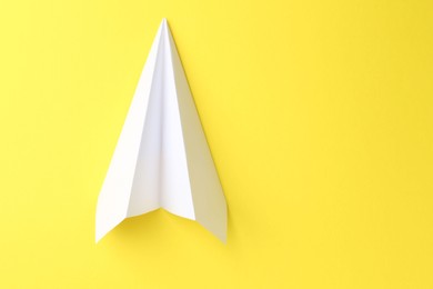 Photo of One handmade paper plane on yellow background, top view. Space for text