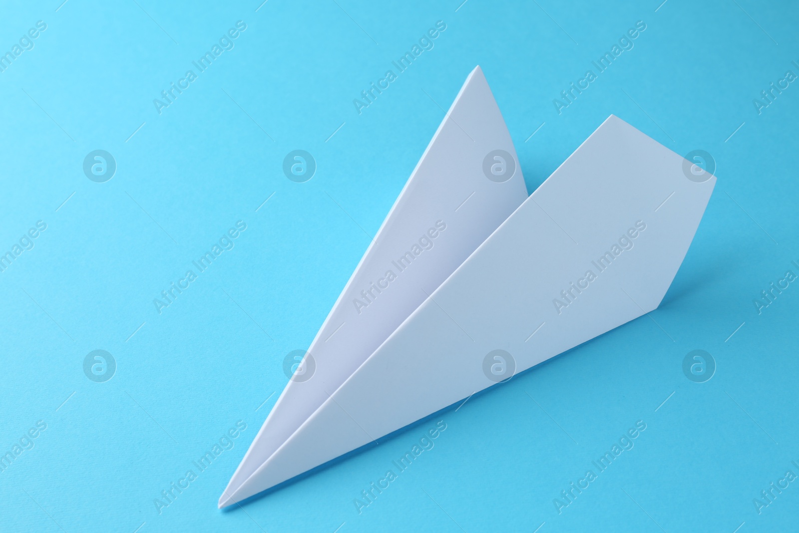 Photo of One handmade paper plane on light blue background