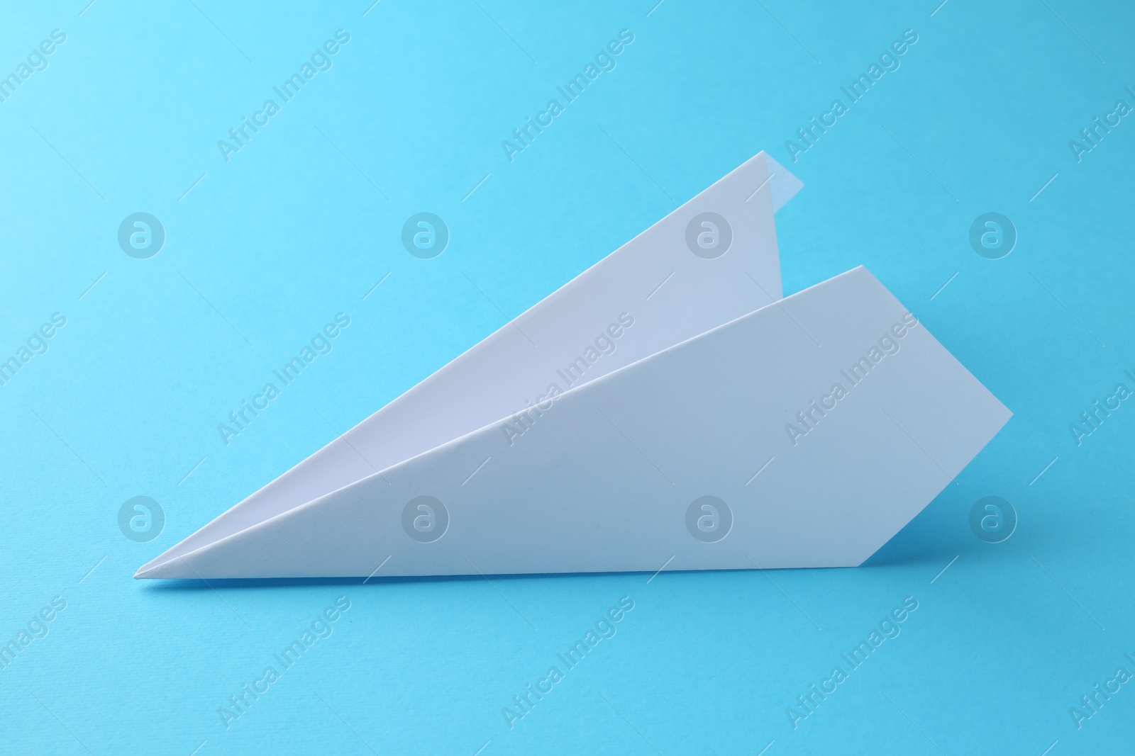 Photo of One handmade paper plane on light blue background