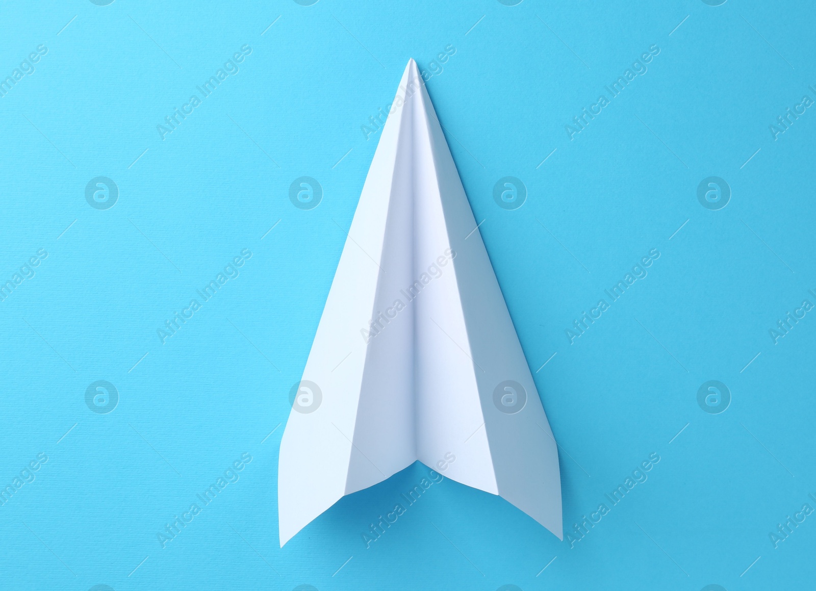 Photo of One handmade paper plane on light blue background, top view