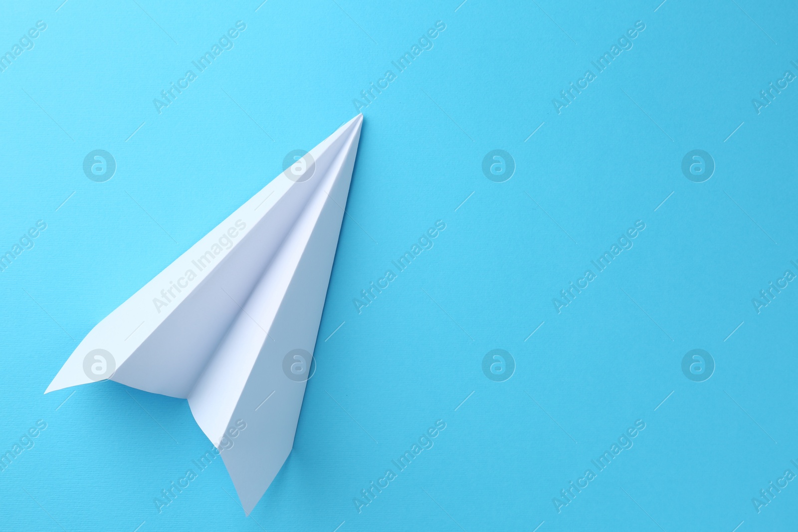 Photo of One handmade paper plane on light blue background, top view. Space for text