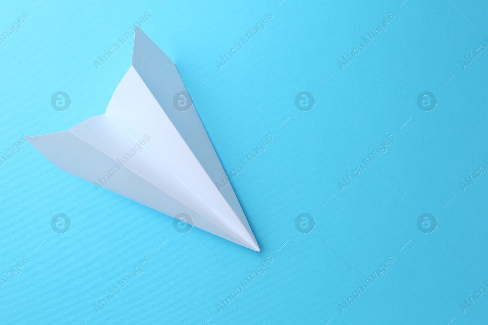 Photo of One handmade paper plane on light blue background, top view. Space for text