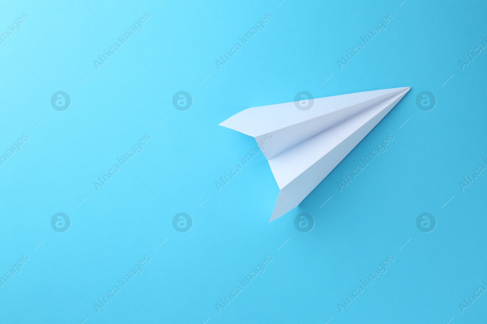 Photo of One handmade paper plane on light blue background, top view. Space for text