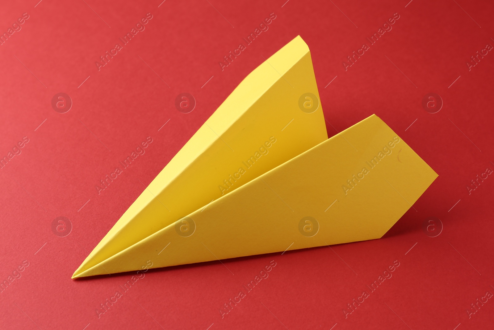 Photo of One handmade yellow paper plane on red background