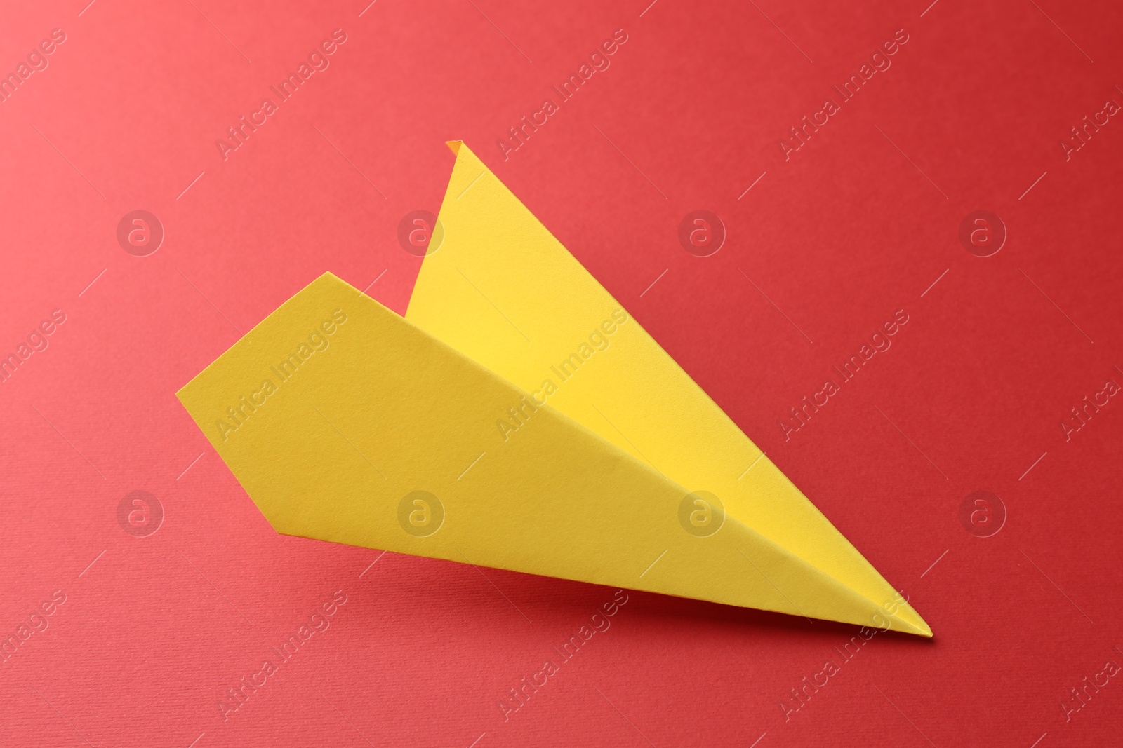 Photo of One handmade yellow paper plane on red background