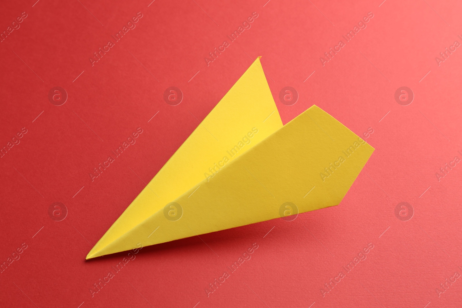 Photo of One handmade yellow paper plane on red background